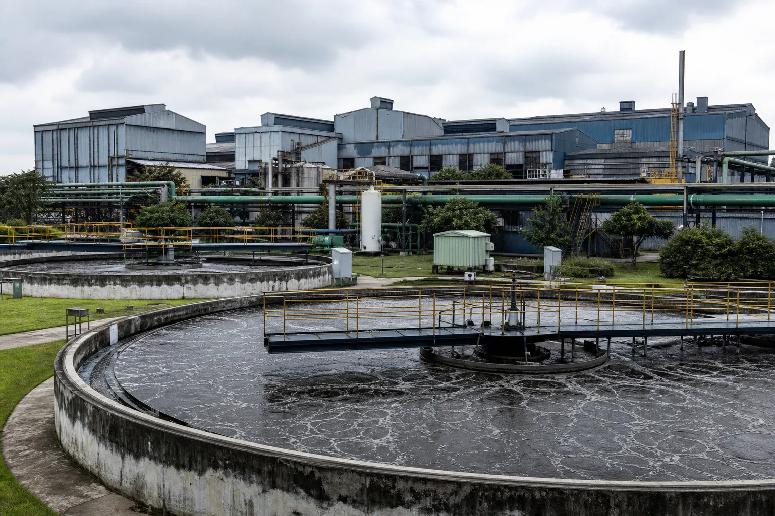 Industrial effluent treatment plant with aeration tanks beside a manufacturing campus
